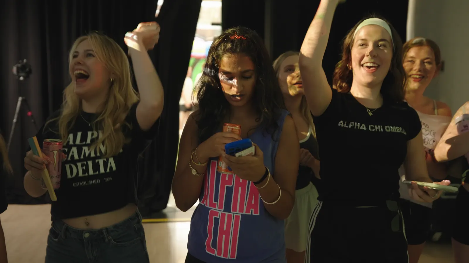 A group of students cheering with their arms in the air inside the projected room.